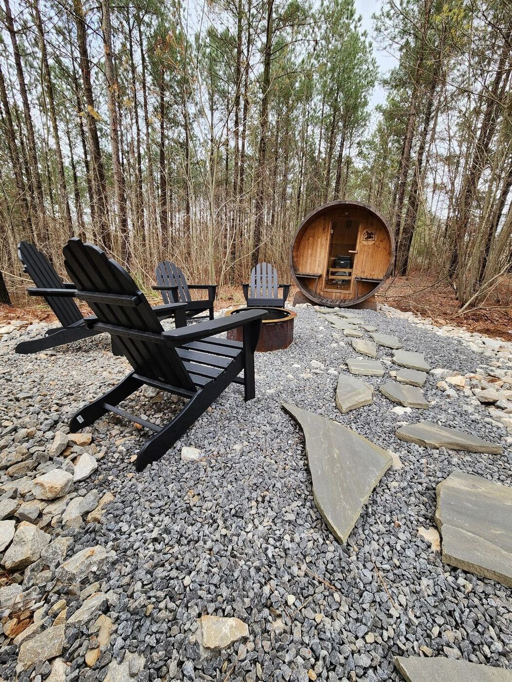 Barrel sauna and Adirondack chairs around a fire pit at the Sasquatch Farm Spa Cabin