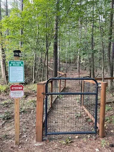 Fenced dog park entrance gate in the woods at Sasquatch Farm RV Park