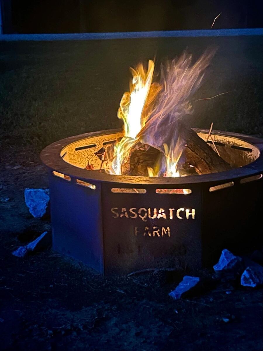 Branded Sasquatch Farm fire pit burning at night