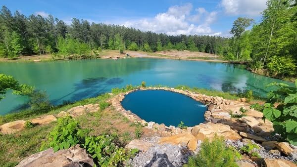 One of the two lakes at Sasquatch Farm RV Park, with a natural stone-edged swimming pool along the shore
